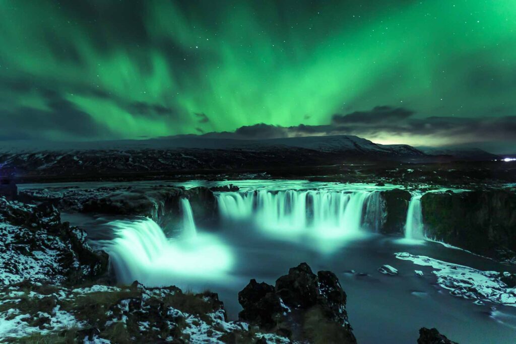 Aurora Boreal na cachoeira na Islândia